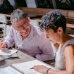 A photo of two people talking and writing.