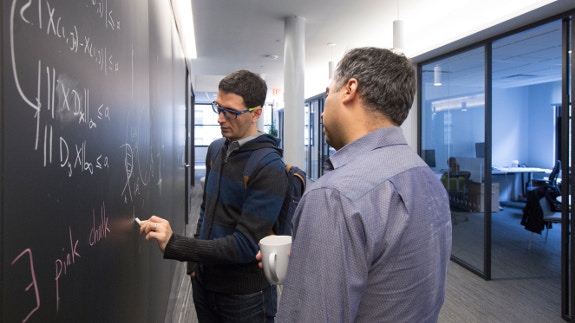 Two people looking at math on a chalkboard