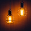 Two similar-looking lightbulbs shine while hanging from the ceiling.