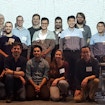 Group of people posing for a photo in front of a projector. Three people's photos are photoshopped on to the right side of the picture