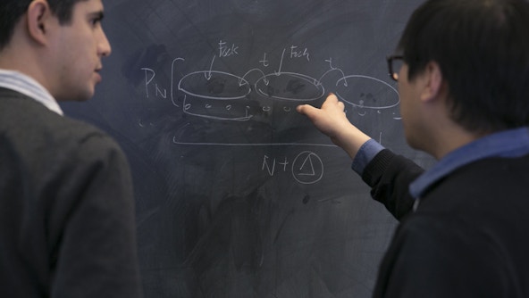 Two people discussing something on a chalkboard