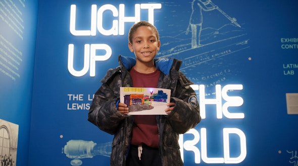 A child visitor to Lewis Latimer House holds up a lighting project completed at the museum.
