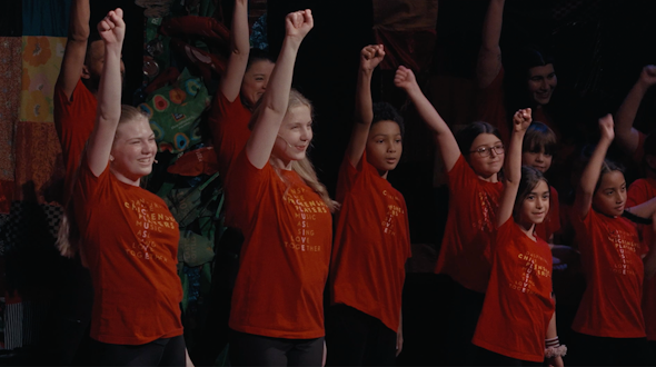 kids in red shirts with their hands raised