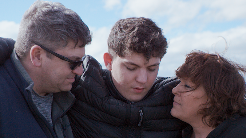 Father, son and mother hugging and looking down